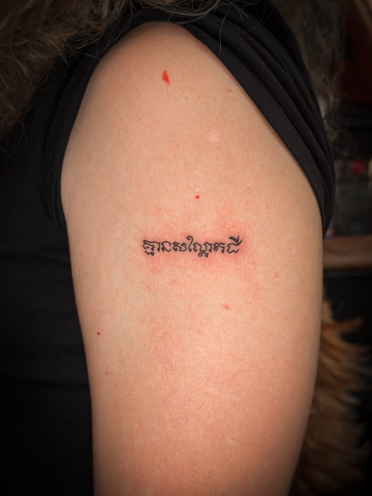 The “No peanut” Khmer script tattoo on the client's upper arm.
