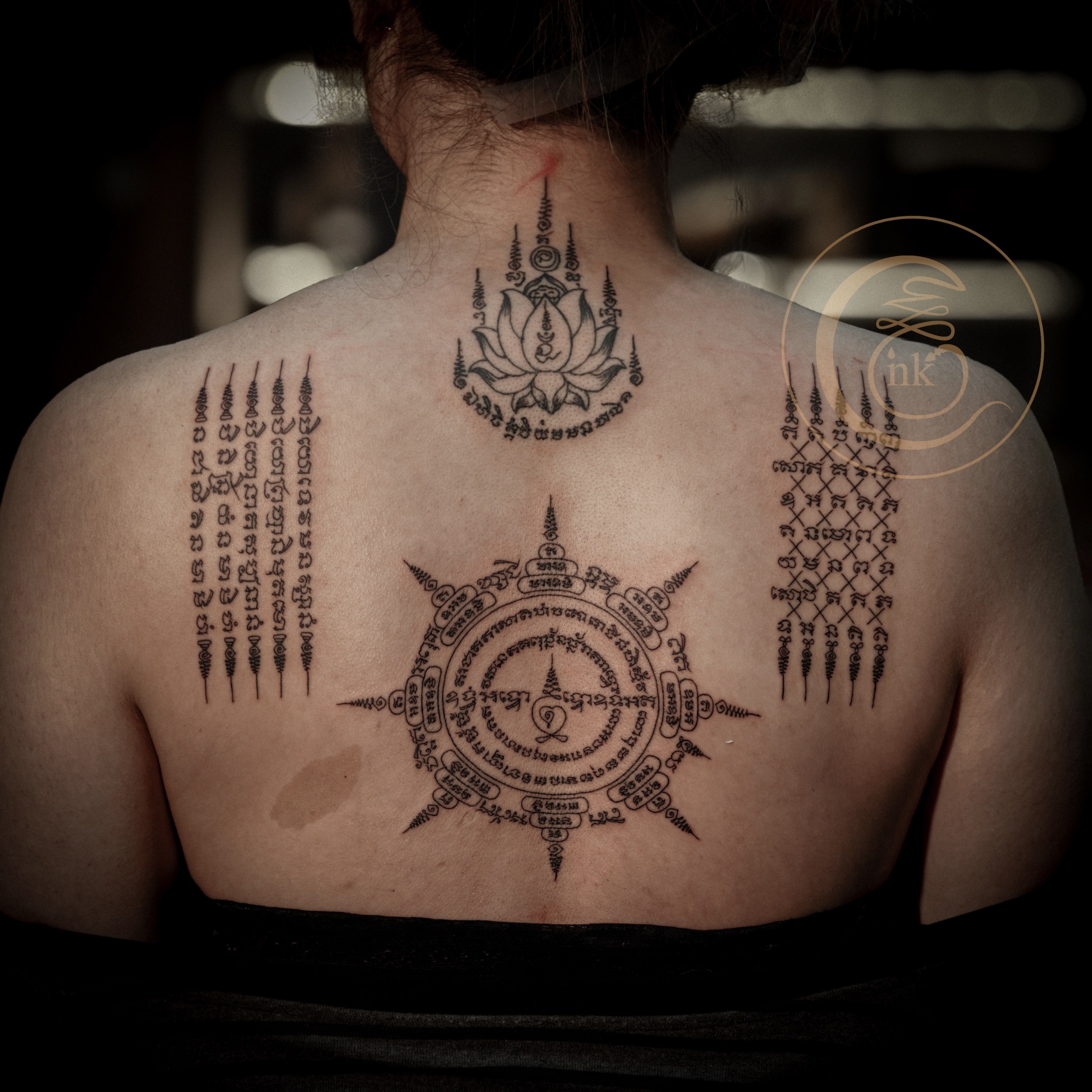 Close-up of the lotus, five-row, cross, and eight-direction Sak Yant tattoos