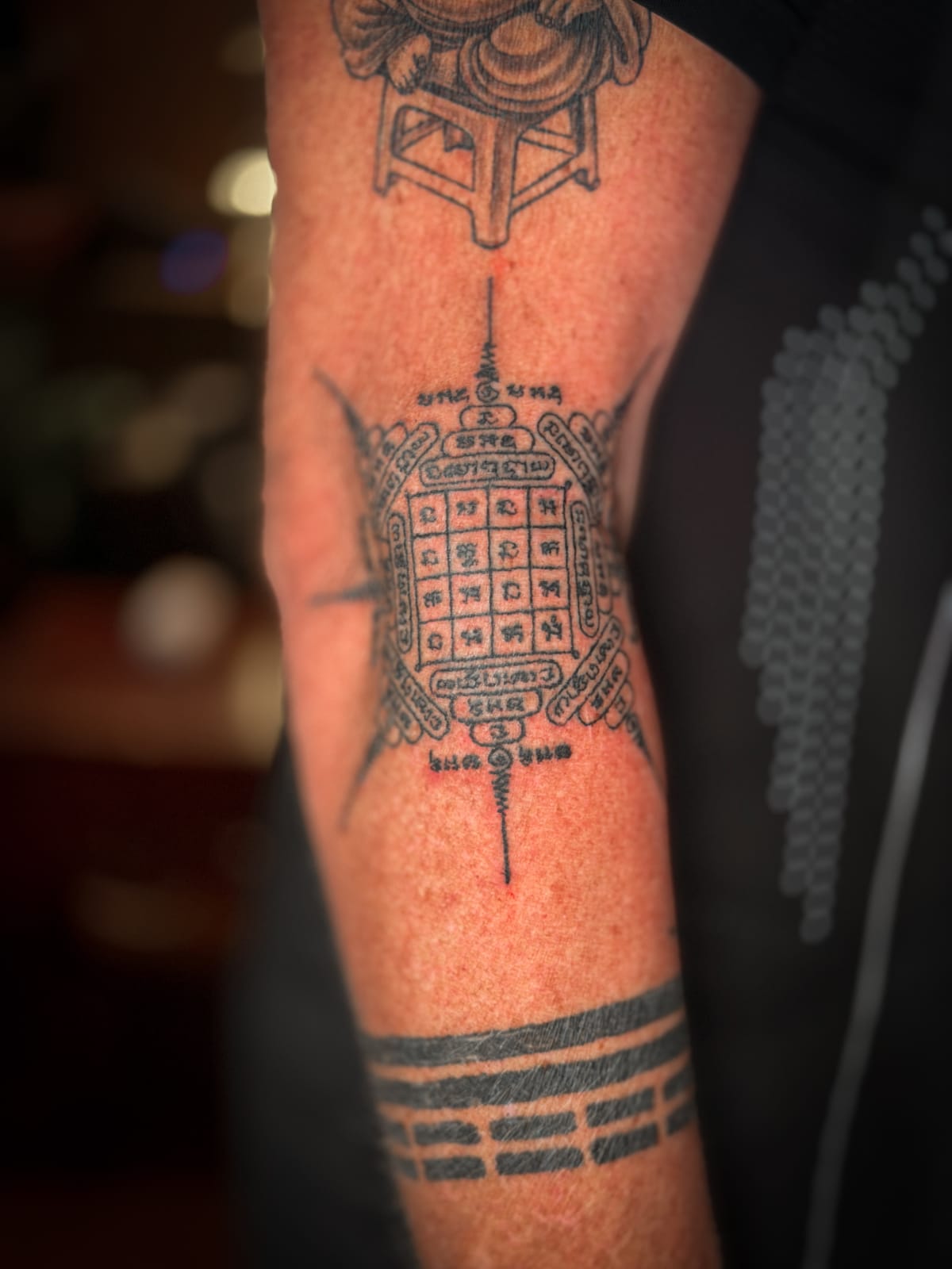 Close-up of a traditional Khmer eight-direction yantra tattoo on an arm.